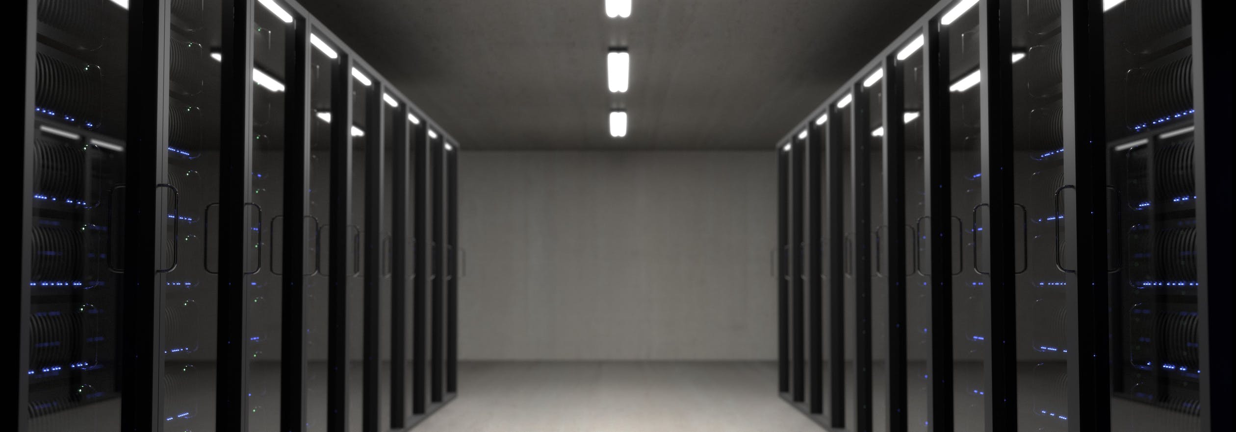Es ist ein Serverraum zu sehen, welcher dunkel gehalten ist und viele Server beinhaltet.