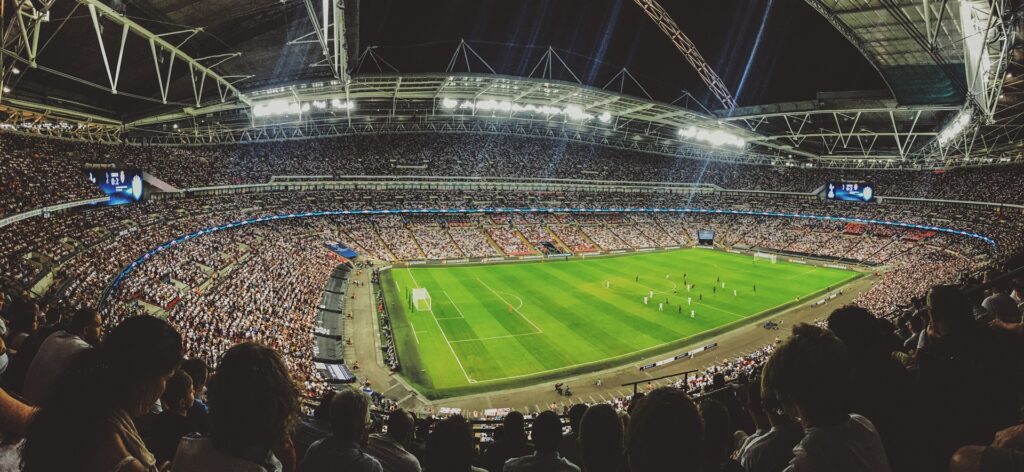 Montre un stade de football plein à craquer sous un éclairage de projecteurs