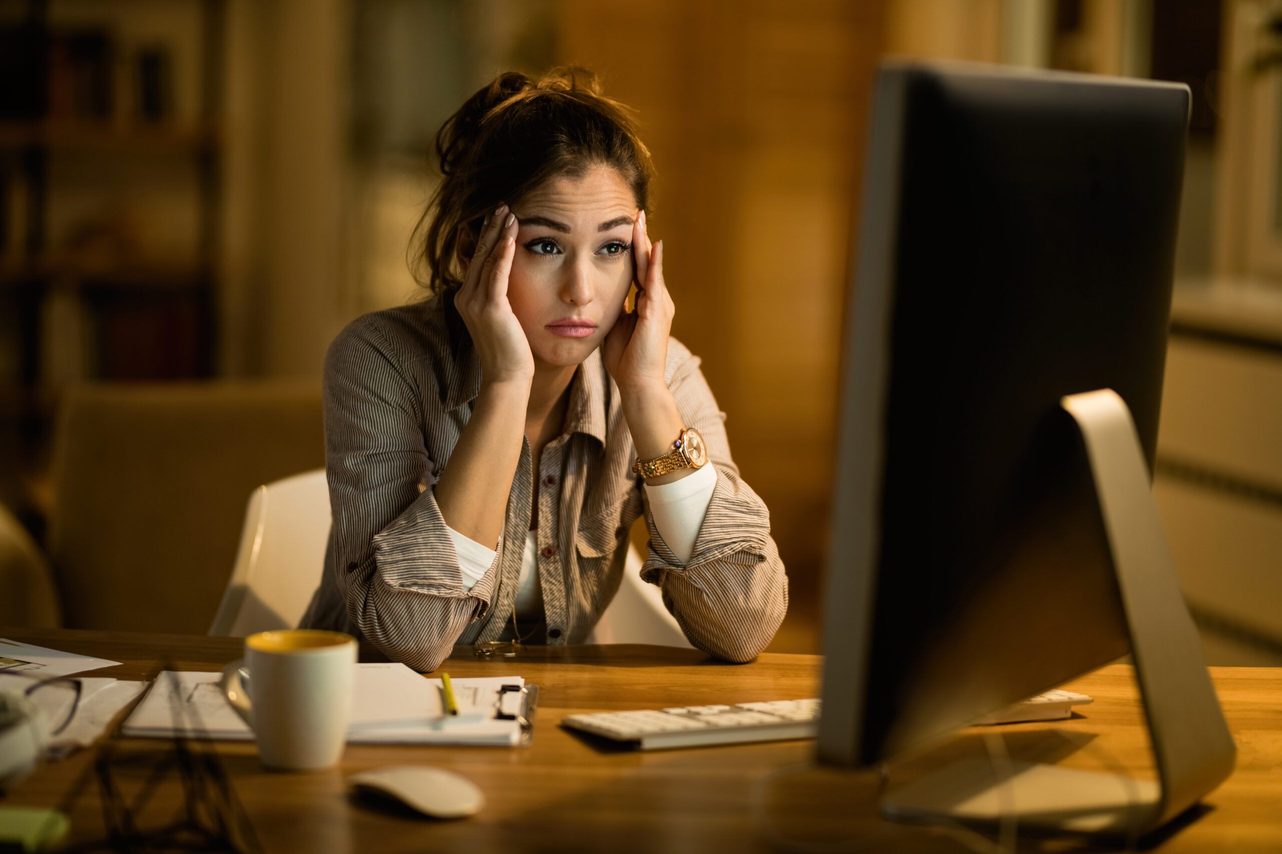 Nuori nainen istuu hämmentyneenä kannettavan tietokoneen ääressä.